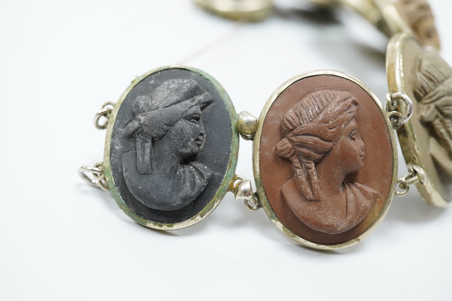 A Victorian base metal bracelet, set with seven graduated lava cameos, carved with the busts of lady's to dexter and sinister, approximately 16.5cm.